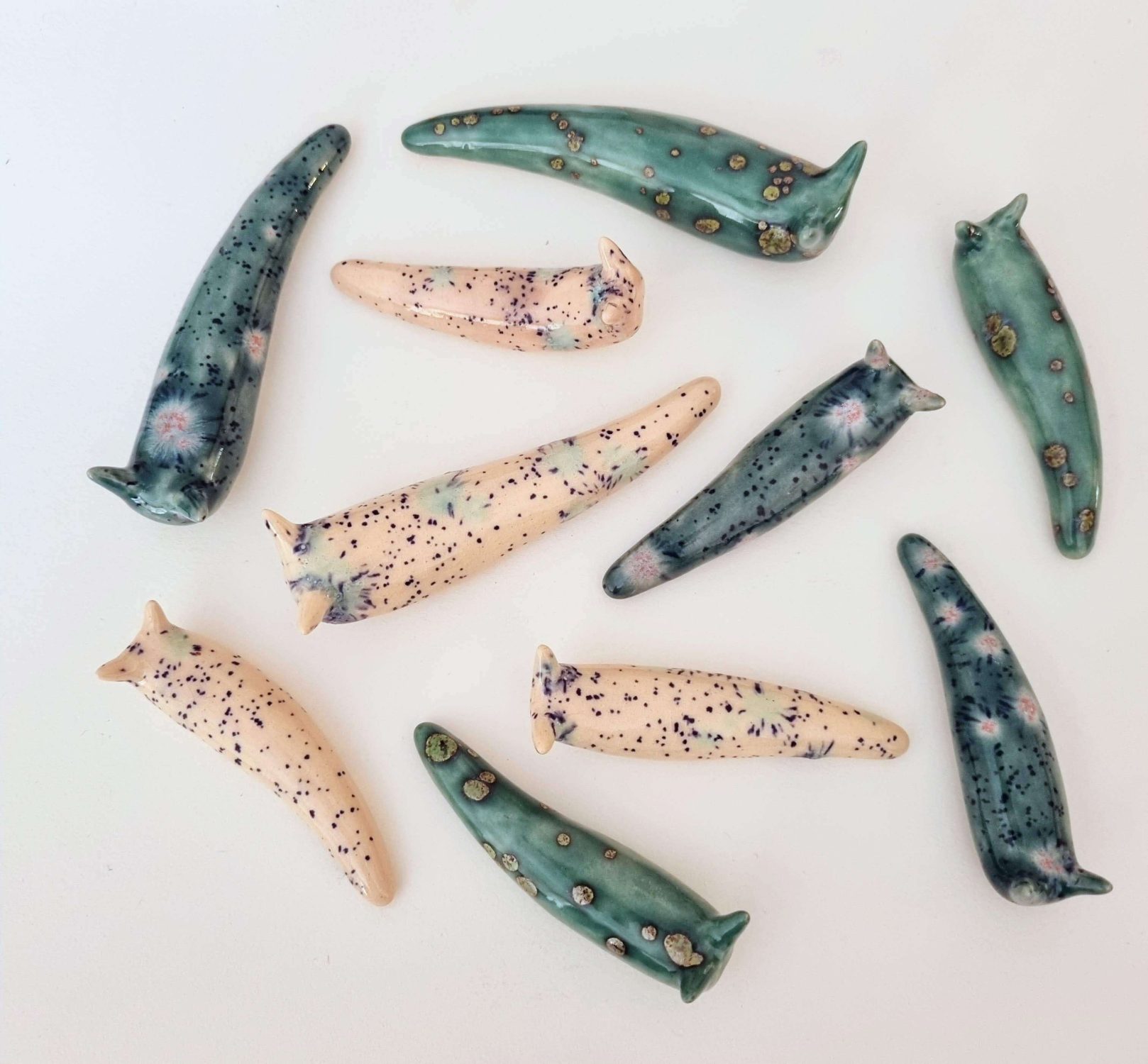 ceramic Slugs in pink and blue crystal gem glaze on white background. Multiple slugs from top view