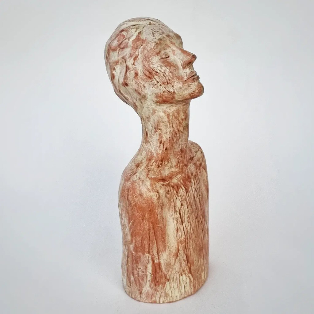 Ceramic figurative sculpture of womapale yellow and resld clay figurative sculpture of person praying on white background