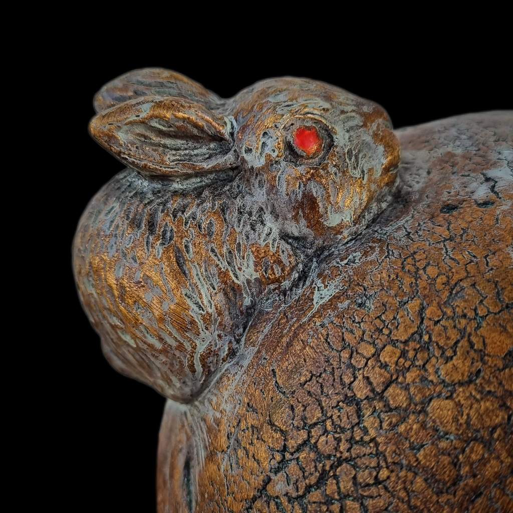 Close up of rabbit sculpture in faux bronze and green patina finish