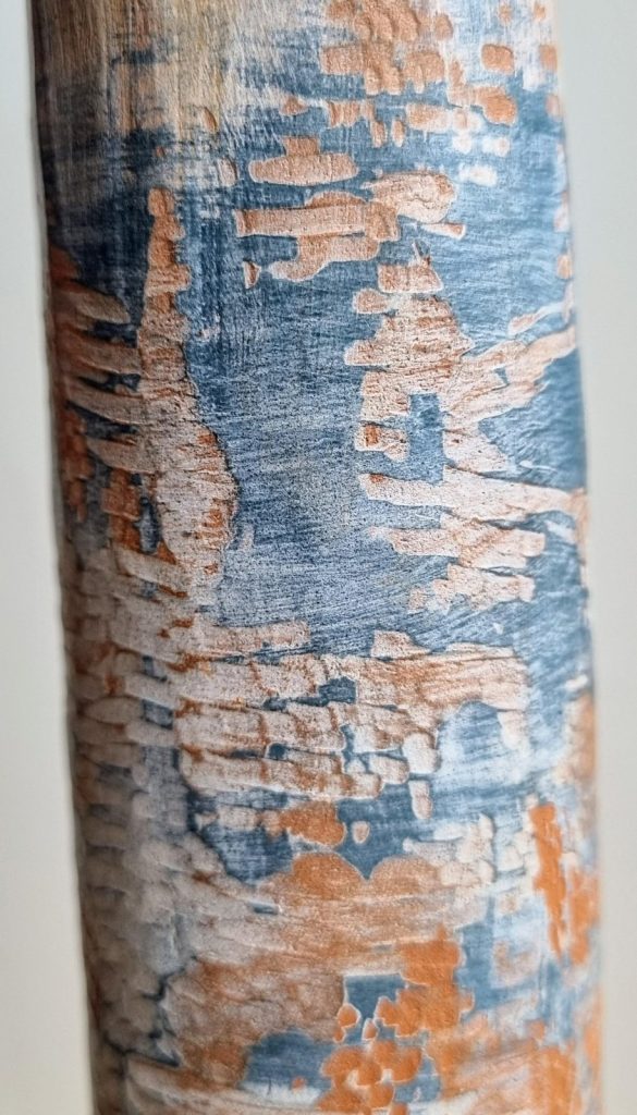 Close-up of textured pottery surface showcasing a blend of blue and orange hues with natural, organic patterns resembling accidental mark making.